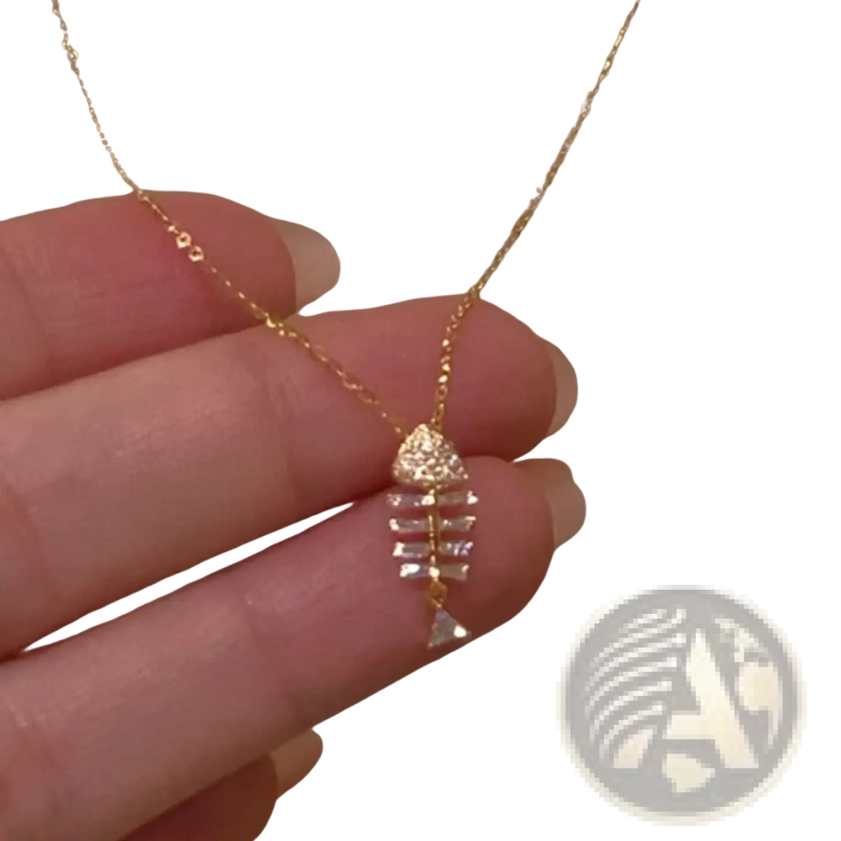 A delicate gold chain necklace with a fishbone-shaped pendant adorned with clear crystals