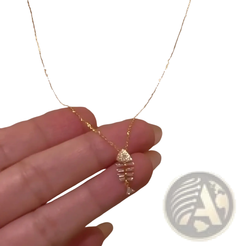 A delicate gold chain necklace with a small sparkling fishbone pendant adorned with clear crystals