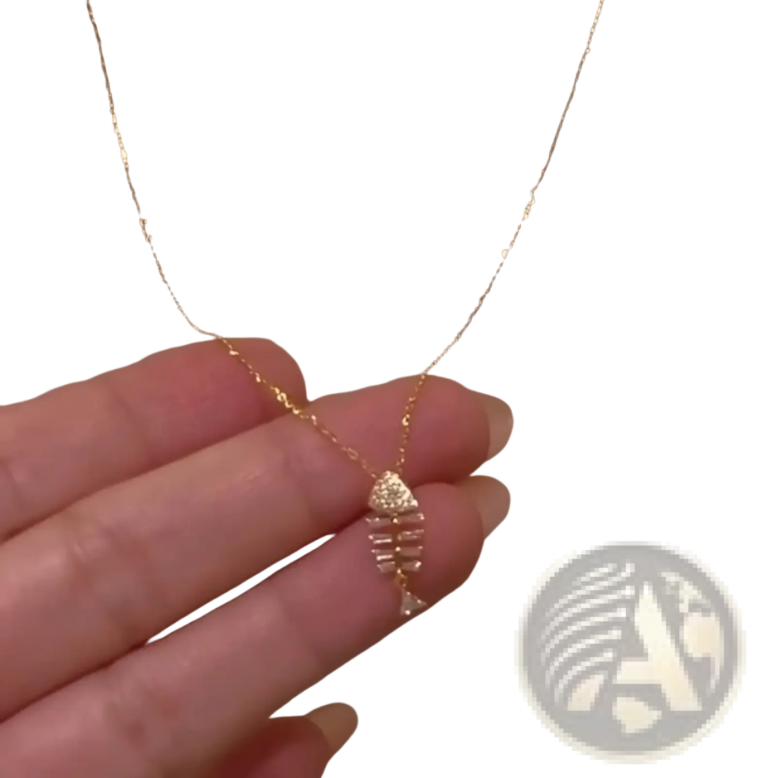 A delicate gold chain necklace with a small sparkling fishbone pendant adorned with clear crystals