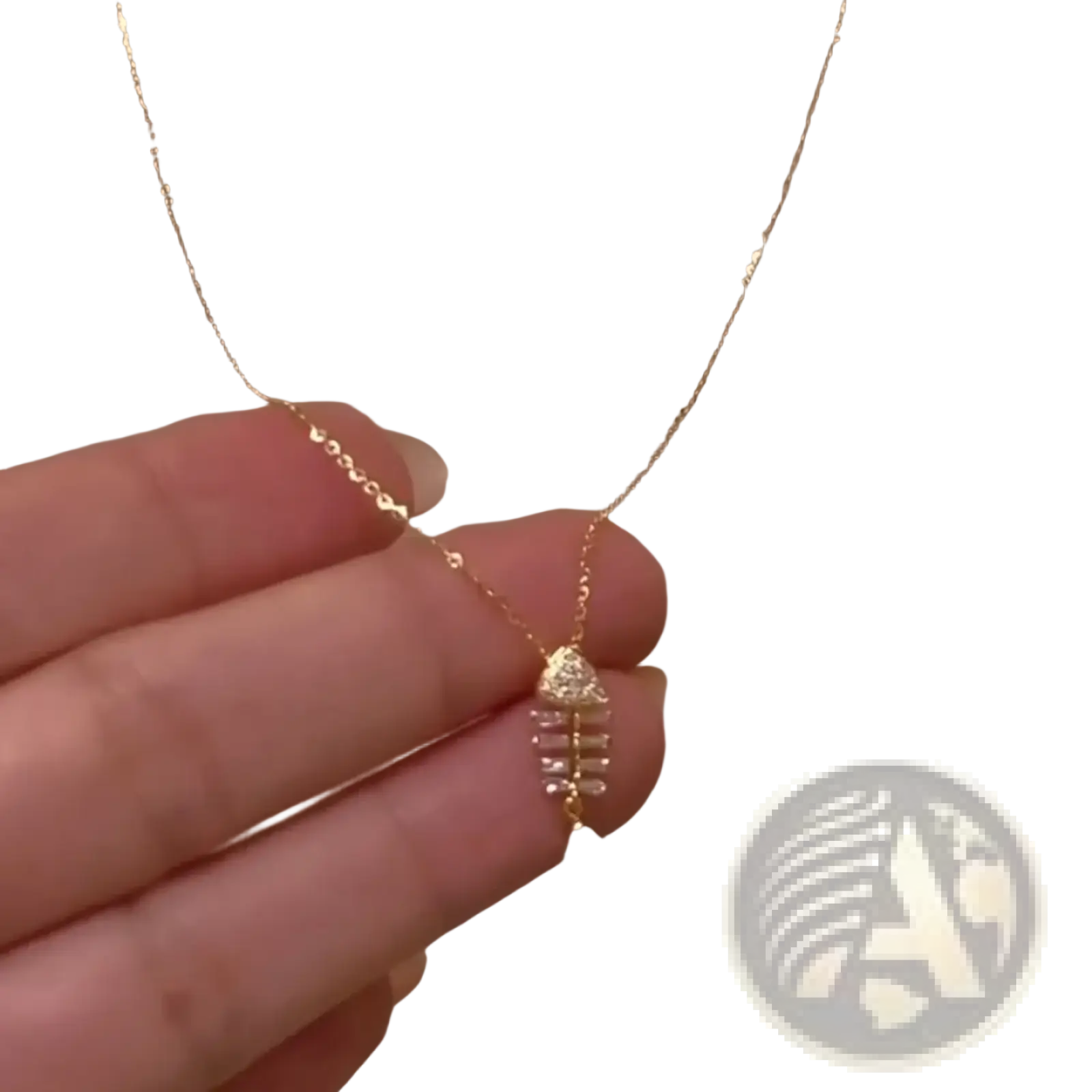 A delicate gold chain necklace with a small crystal-adorned fishbone pendant in clear crystals