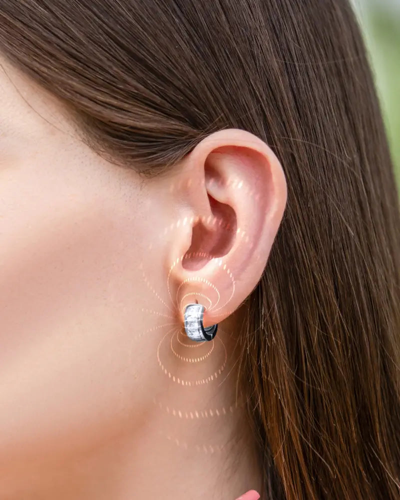 Silver crystal magnetic therapy huggie earrings with silver tone and black and white striped pattern