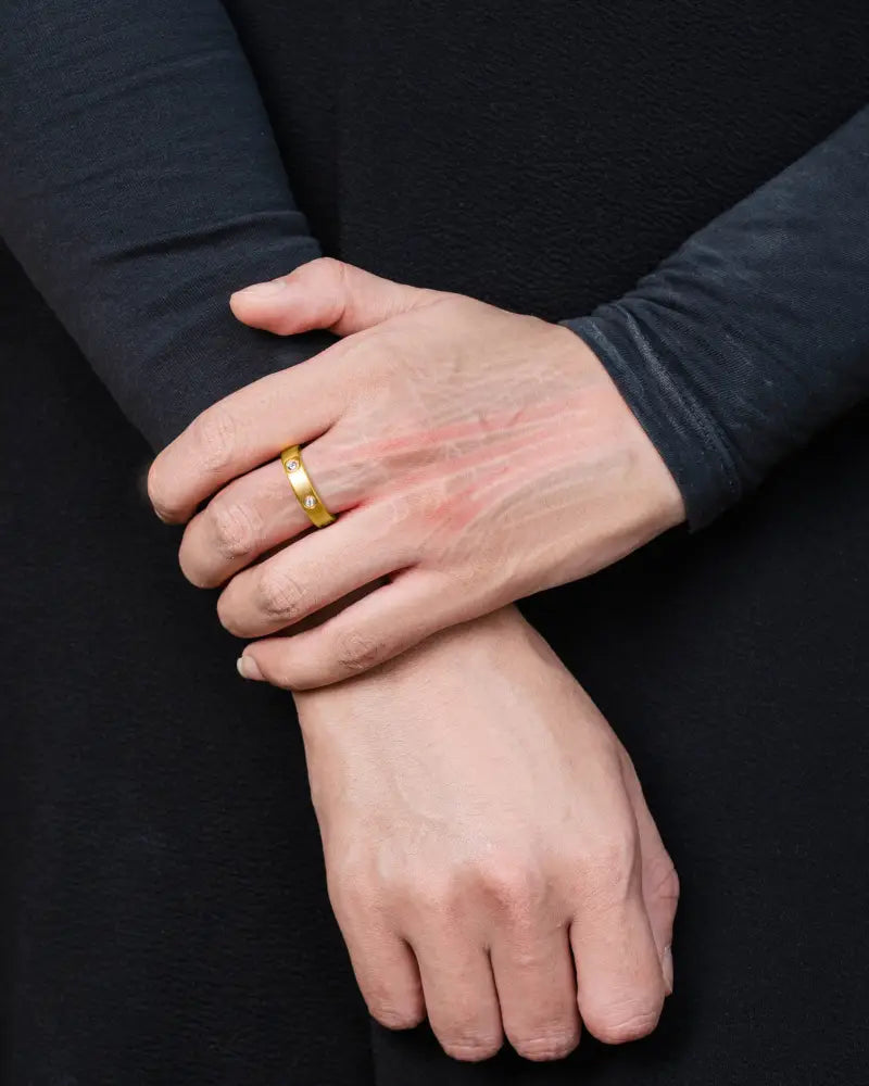 A sleek gold crystal magnetic therapy ring with neodymium magnets and three small sparkling diamonds on its surface