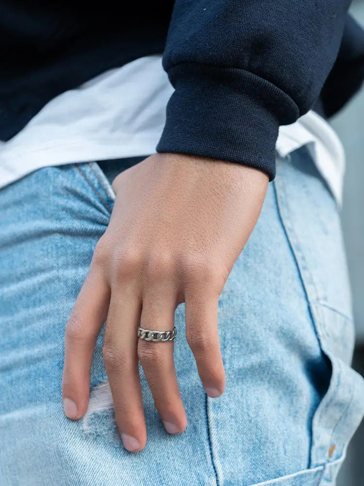 A sleek polished silver cuban link stainless steel chain ring worn on a finger