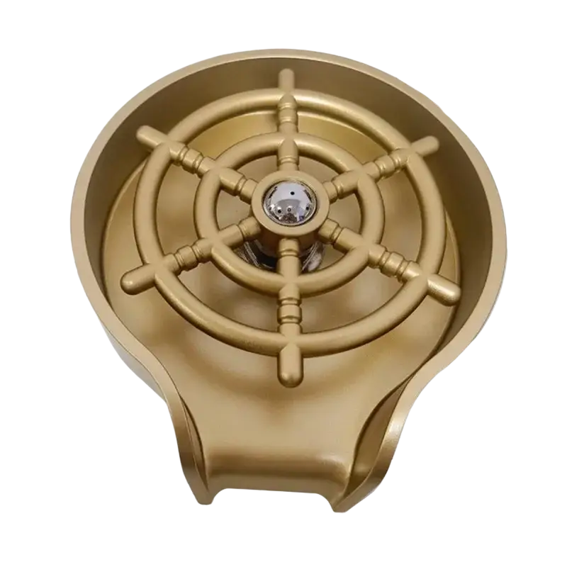 Gold-colored ship wheel-shaped metallic sink drain cover with central knob for high pressure automatic cup washer