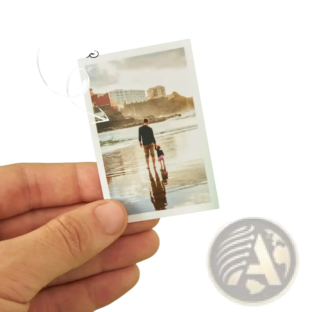 A hand holds a custom couple photo print with white border featuring a man and child walking on a beach