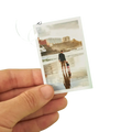 A hand holds a custom couple photo print with white border featuring a man and child walking on a beach