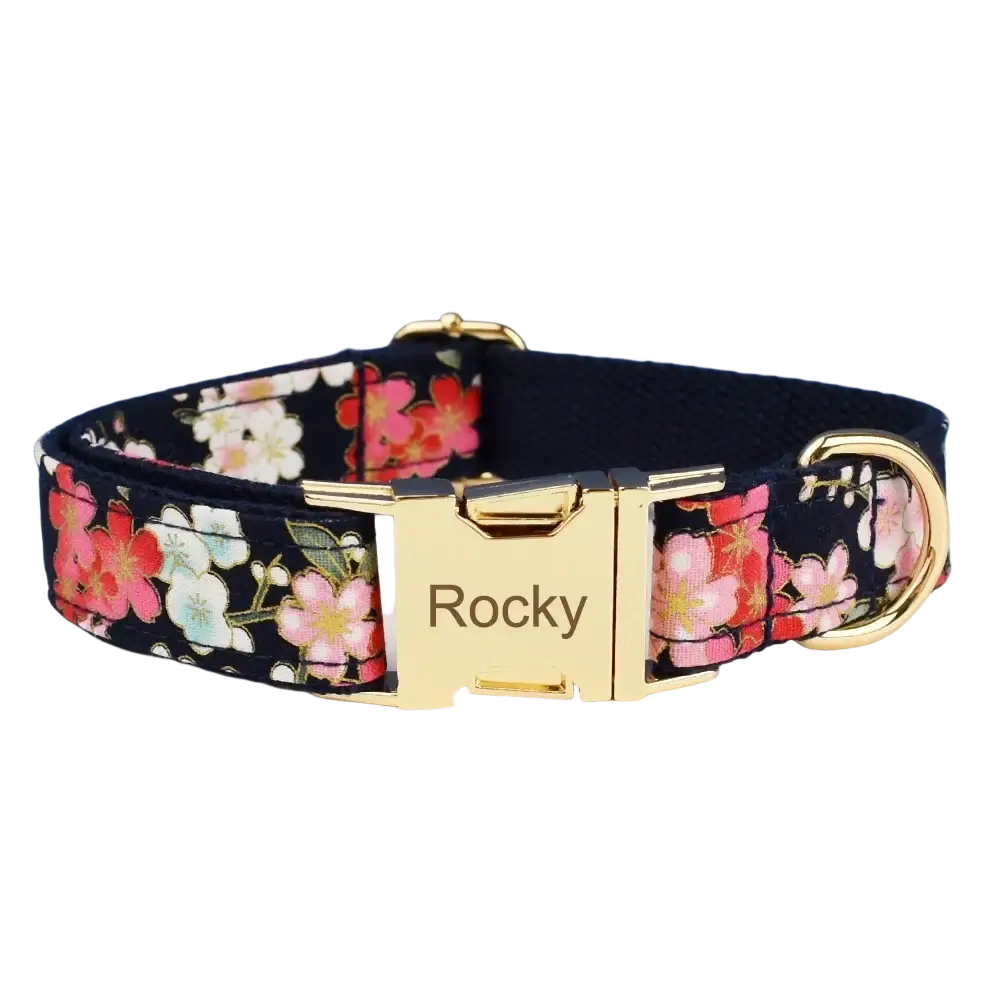 A navy blue floral dog collar with pink and white blossoms and a gold-tone engraved buckle for designer personalized pet accessories
