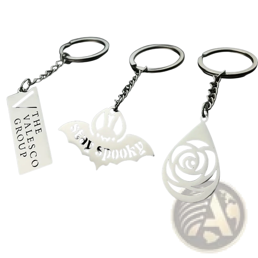Three silver-toned custom engraved metal keychains with personalized designs including valesco group and stay spooky tags