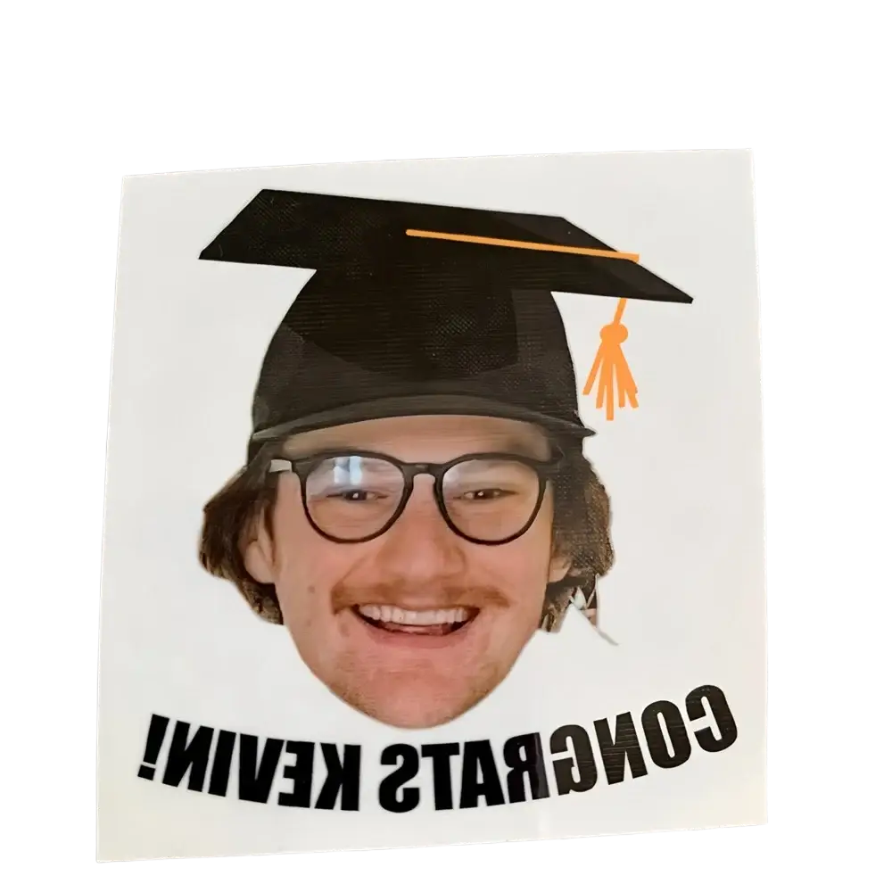 A white custom graduation face tattoo sticker featuring a smiling man with glasses and a black cap with orange tassel