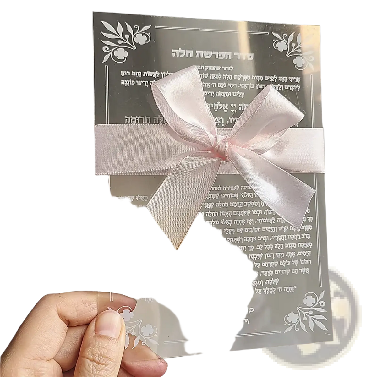 A delicate pink satin bow tied on a transparent acrylic card with engraved hebrew text for wedding and bar mitzvah souvenirs