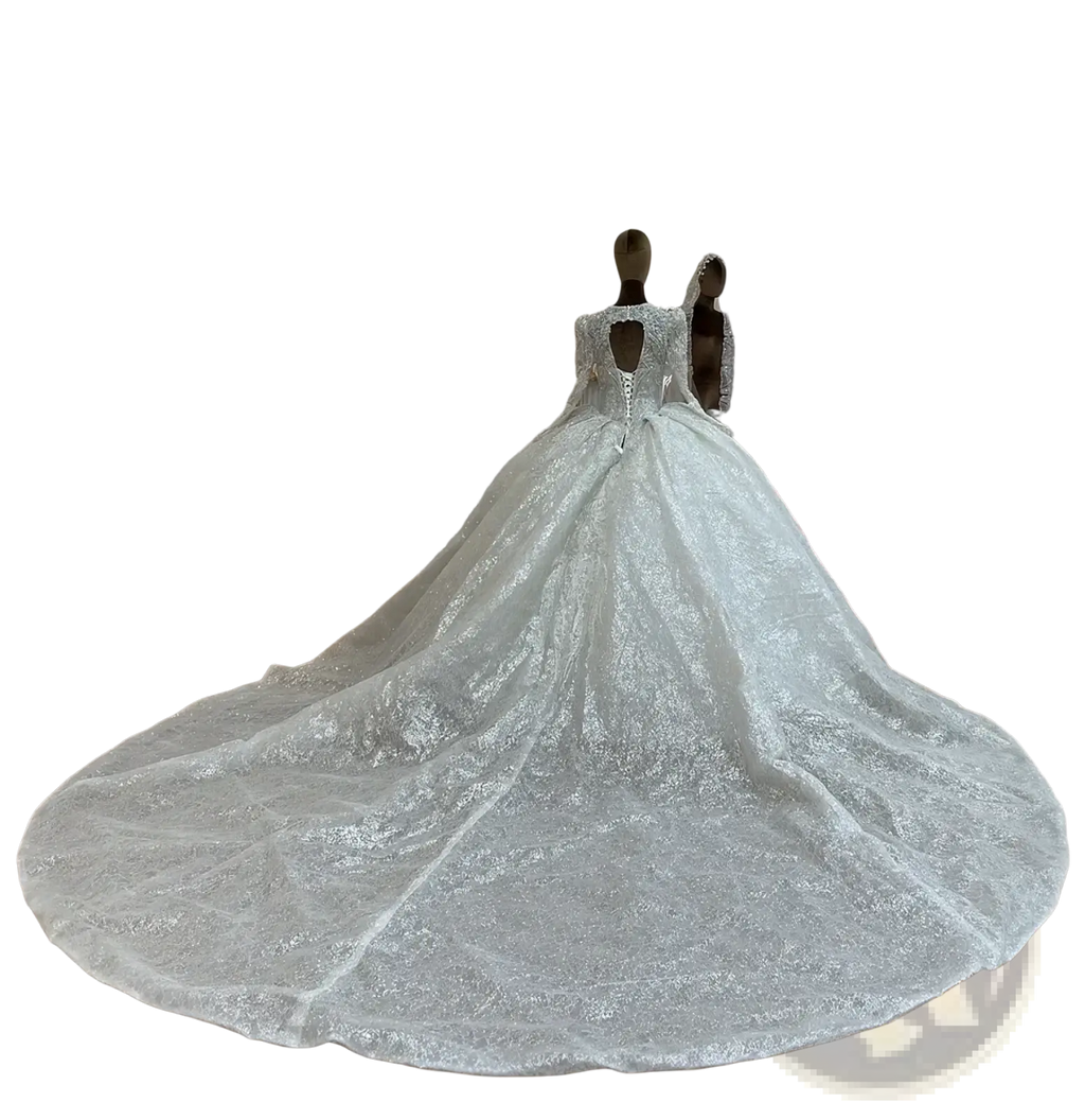 A custom long sleeve lace ball gown wedding dress in shimmering white with intricate lace and a voluminous train