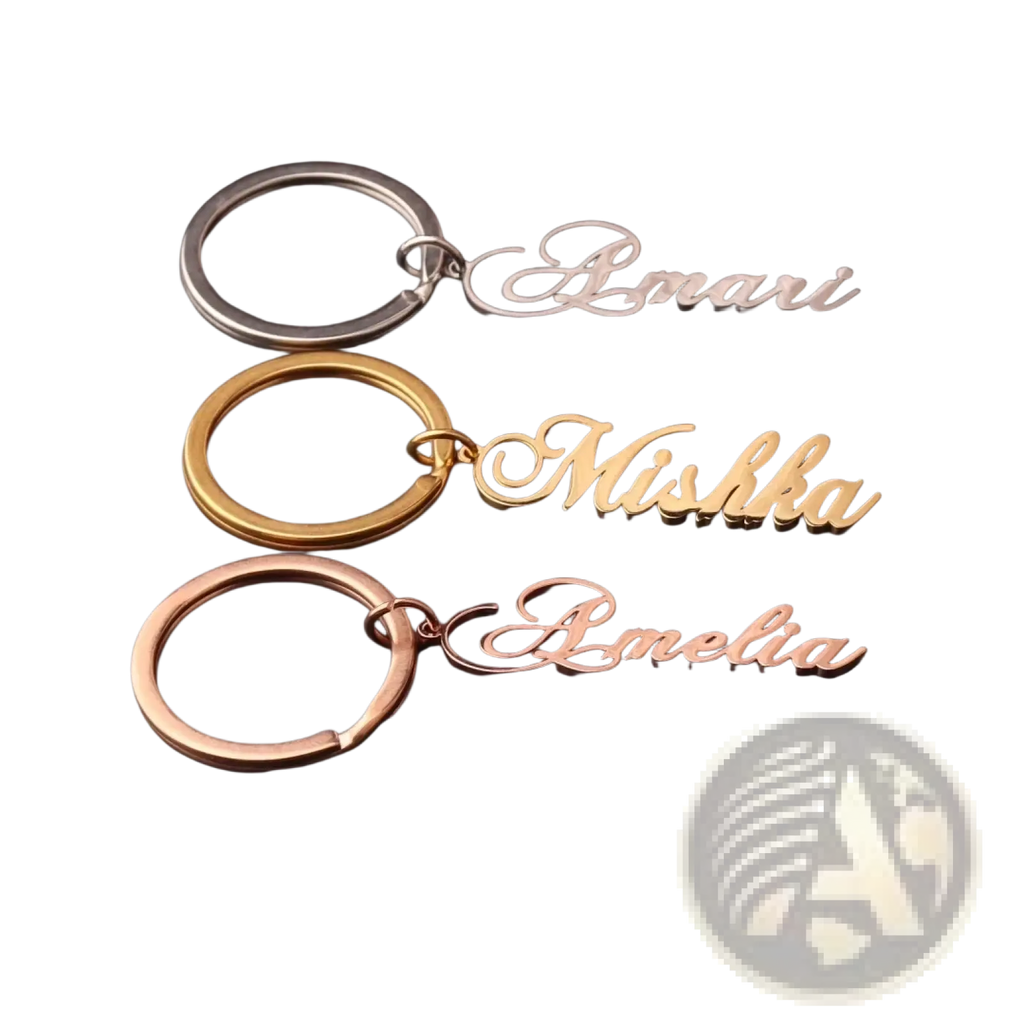 Three custom name keychains in silver gold and rose gold stainless steel with elegant cursive script names amari mishka amelia
