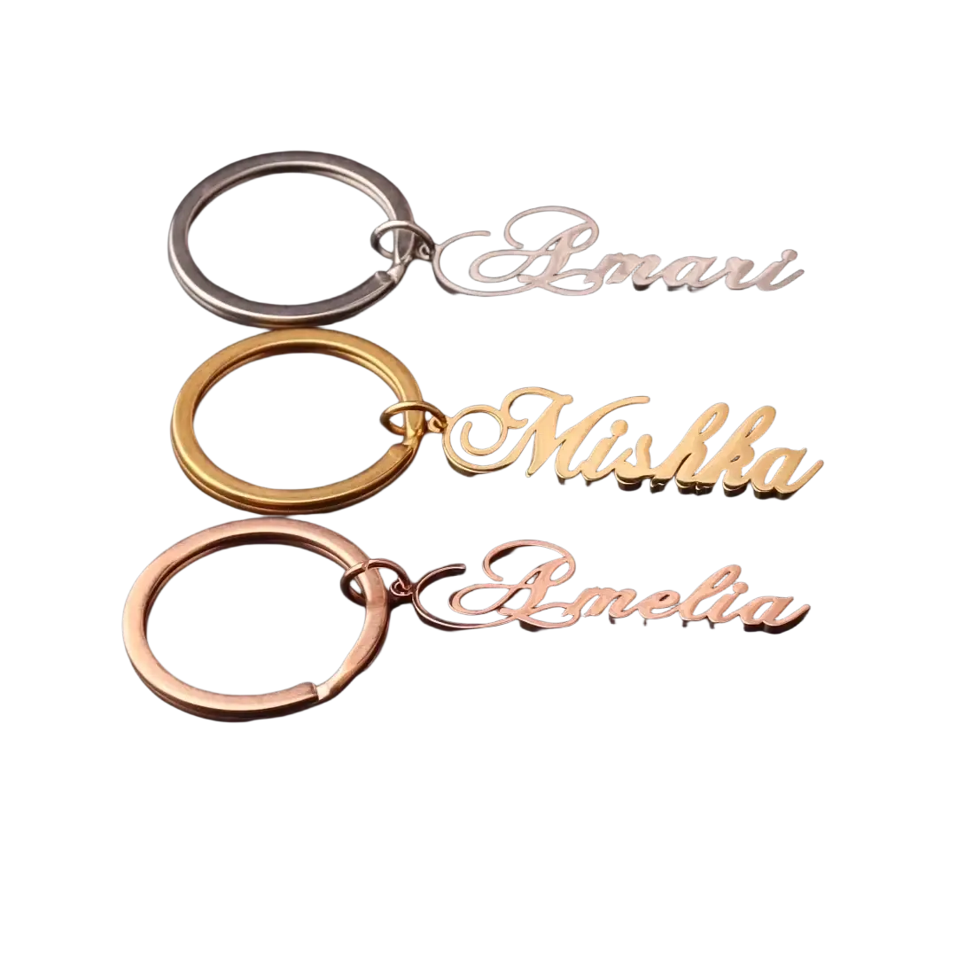 Three custom name keychains in silver gold and rose gold stainless steel with elegant cursive script names amari mishka amelia