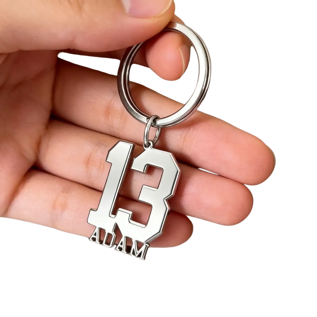 Silver metallic custom number and name keychain with bold cut-out 13 and adam engraved below in athletic font