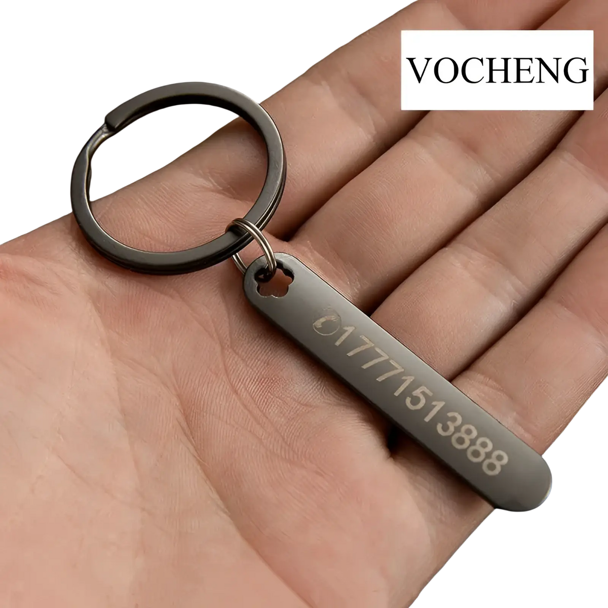 A sleek matte black metal custom phone number keychain with a rectangular laser engraved tag and top cutout