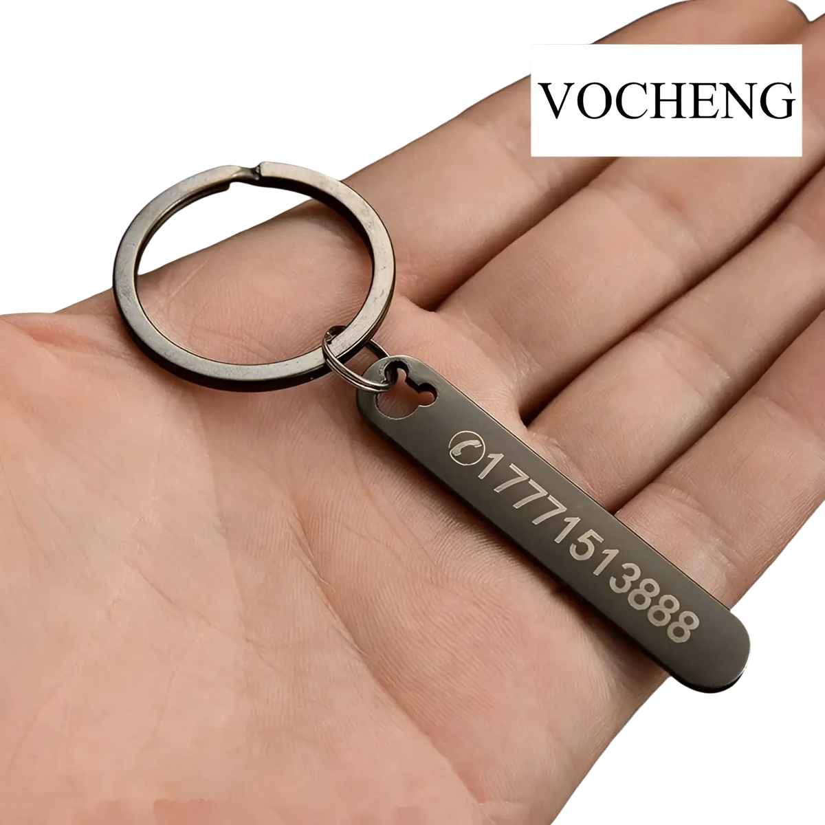 A sleek matte metal keychain with a rectangular laser engraved tag and heart-shaped cutout displaying phone numbers