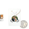 White custom photo wedding favor bag with gold handles and black ornamental leaf designs featuring couple photo