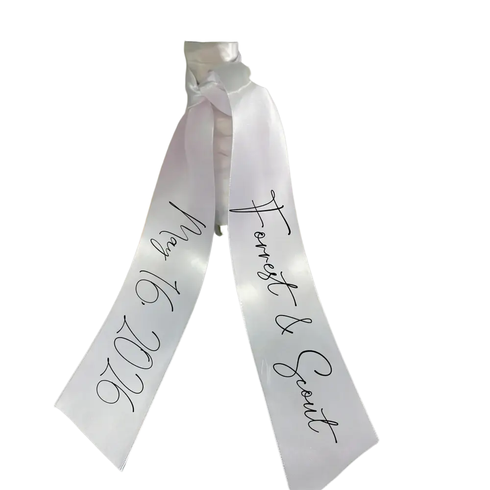 Custom wedding bouquet ribbon made of white satin with black cursive script featuring personal names and date
