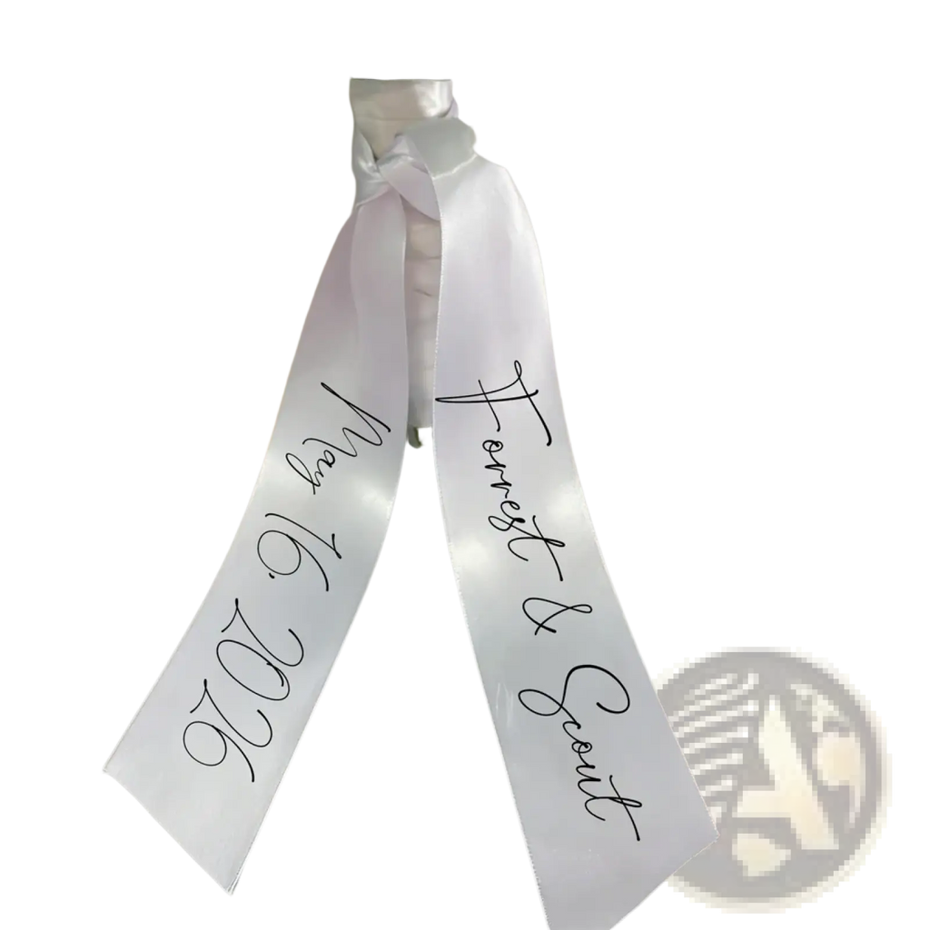 Custom wedding bouquet ribbon made of white satin with black cursive script featuring personal names and date