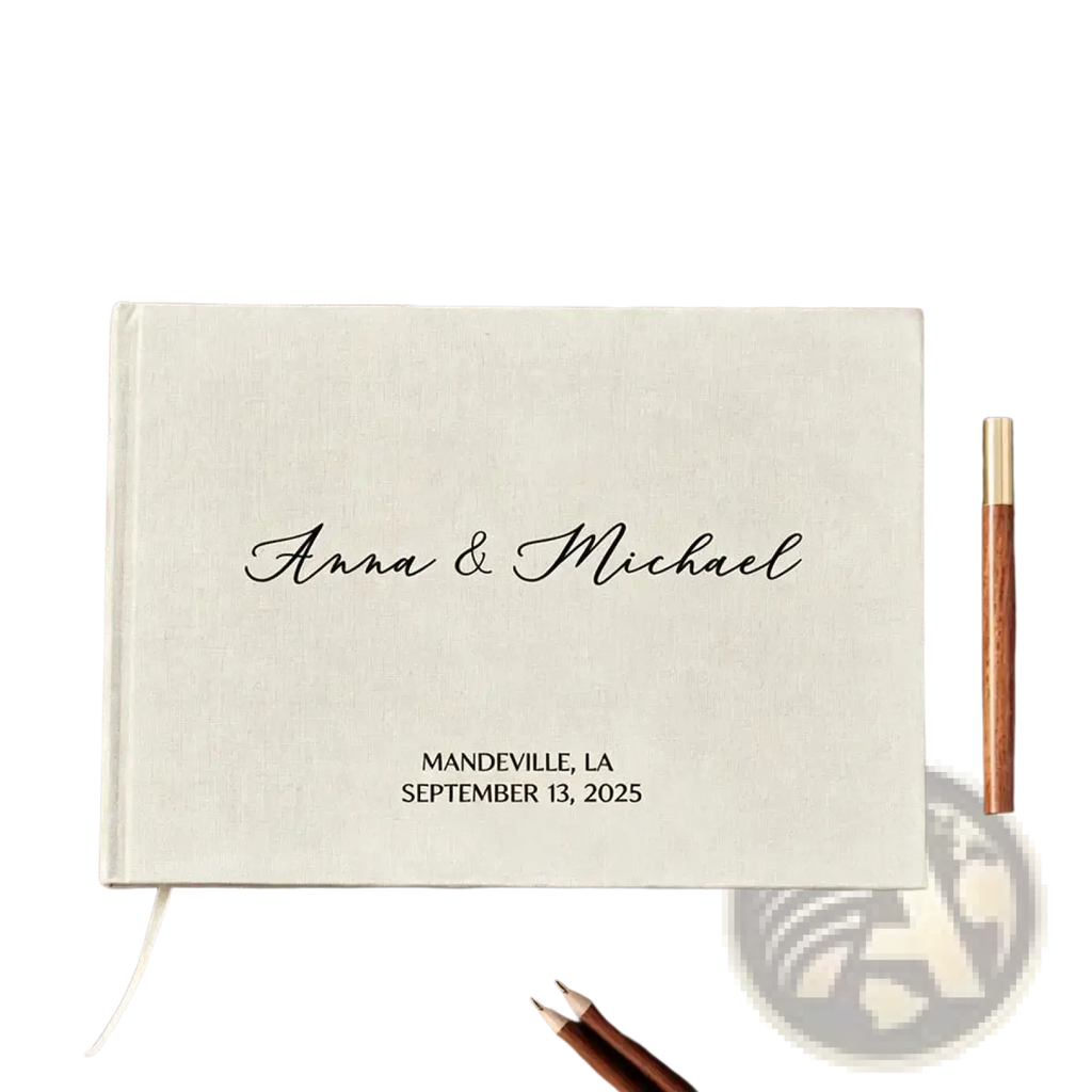 Cream-colored linen-bound custom wedding guest book with black cursive engraving and gold-finished pen for keepsake use