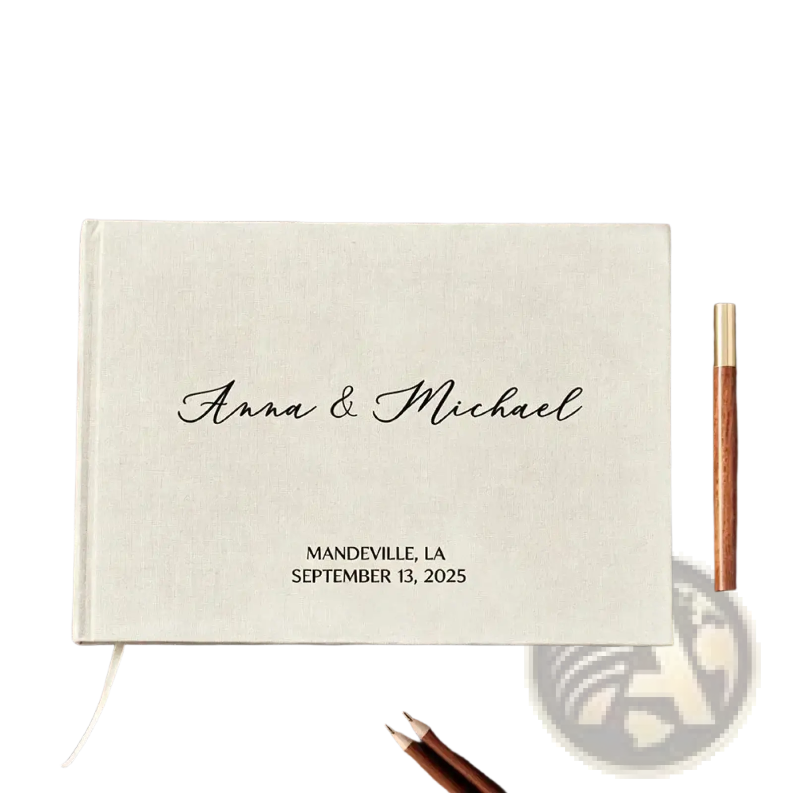 Cream-colored linen-bound custom wedding guest book with black cursive engraving and gold-finished pen for keepsake use
