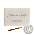 Cream-colored linen-bound custom wedding guest book with black cursive engraving and matching wooden pen photo album