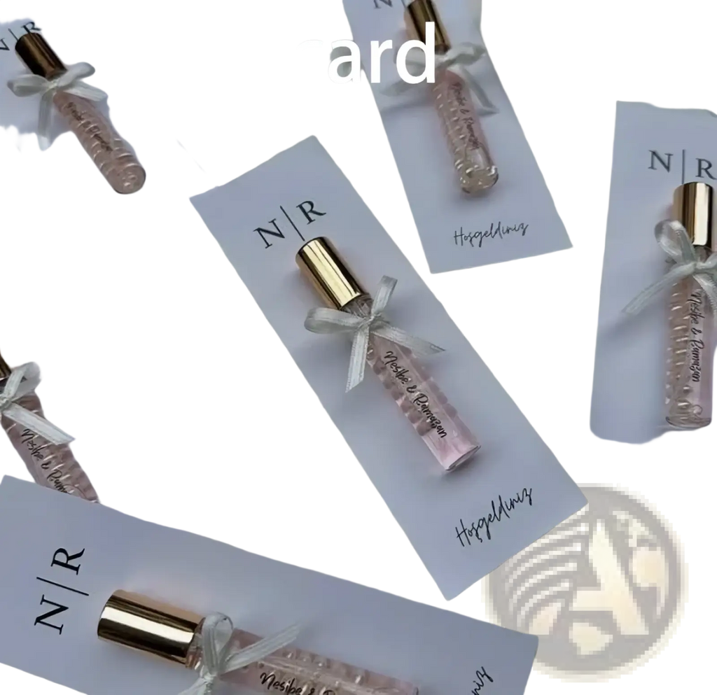 A delicate pink custom wedding perfume favor bottle with a gold cap and white ribbon on a personalized gift card