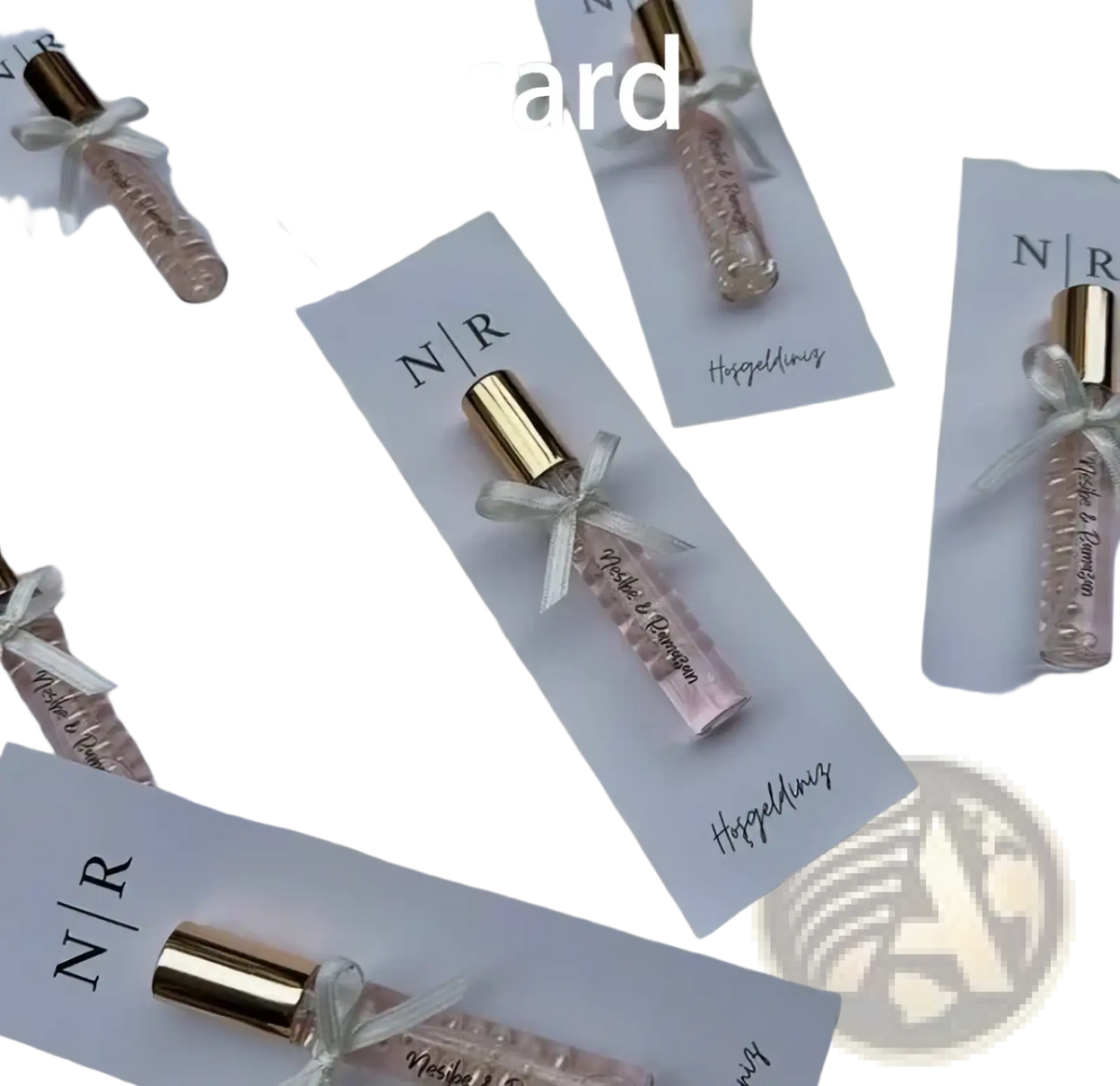 A delicate pink custom wedding perfume favor bottle with a gold cap and white ribbon on a personalized gift card