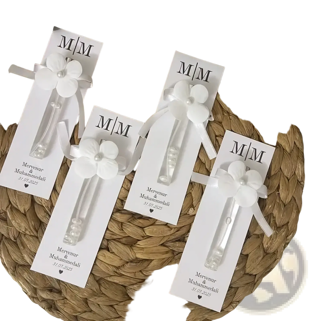 Custom wedding perfume favor bottles with white flower-shaped glass bodies and pearl accents on personalized m/m cards