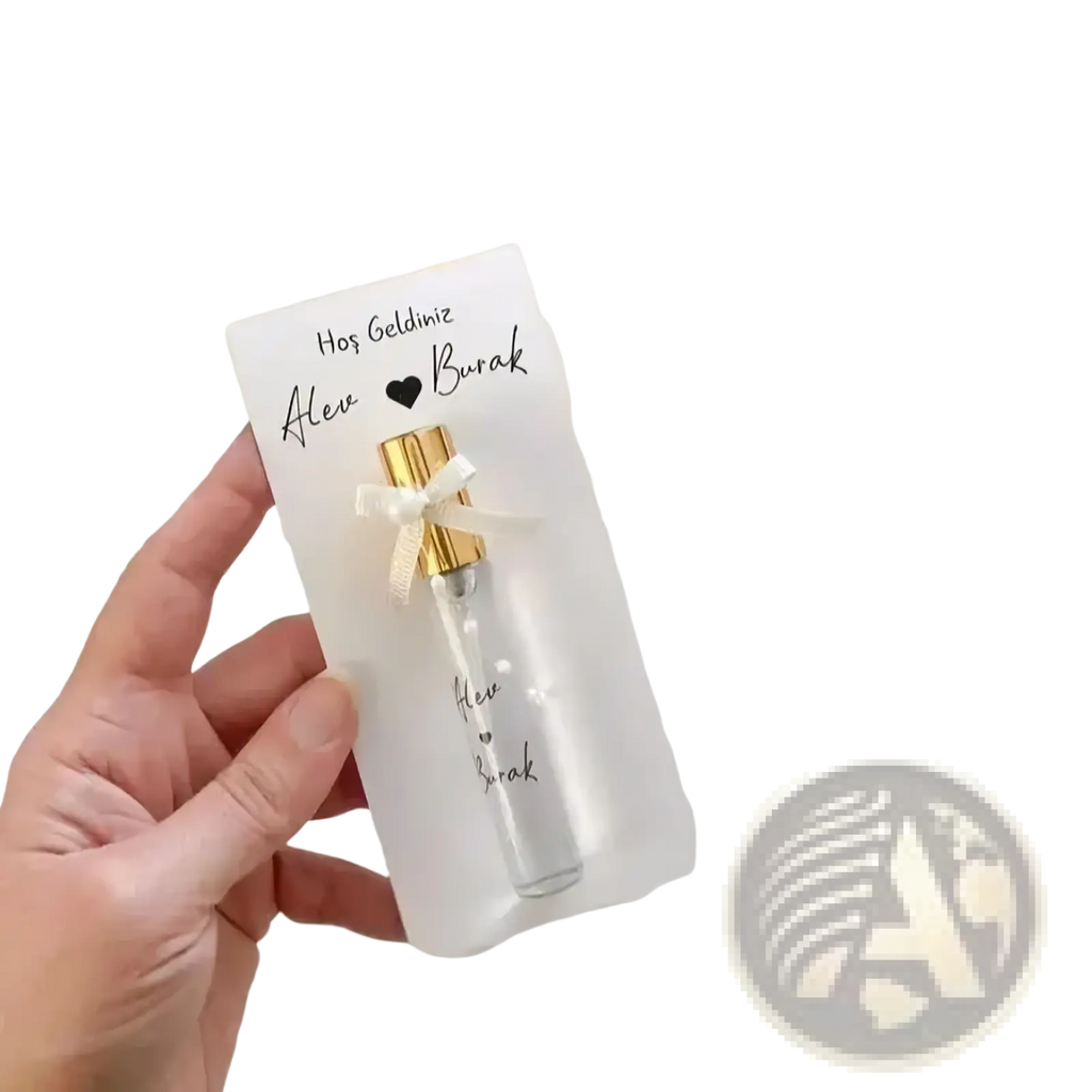 A clear glass custom wedding perfume vial with a gold cap and white ribbon in a personalized gift card