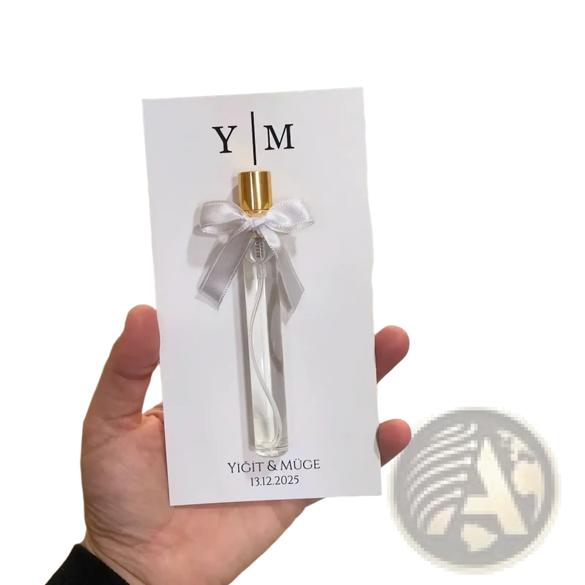 A clear glass custom wedding perfume gift card bottle with a gold cap and silver ribbon bow on a white card