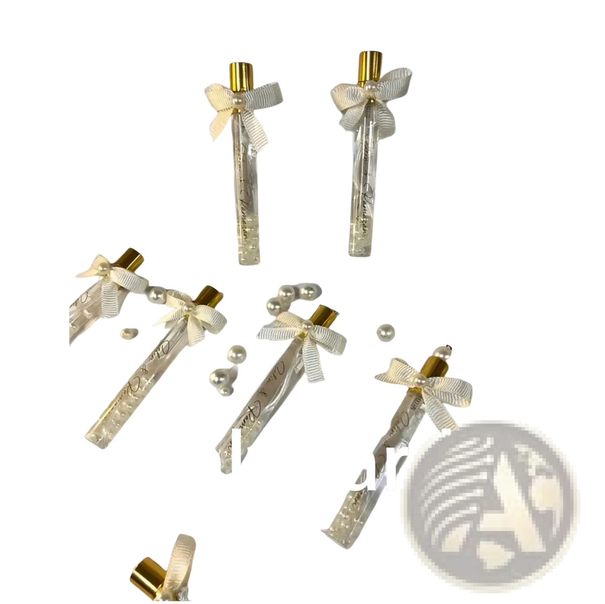 Elegant gold-tipped glass perfume vials with cream ribbons and pearls in white card holders for custom wedding favors