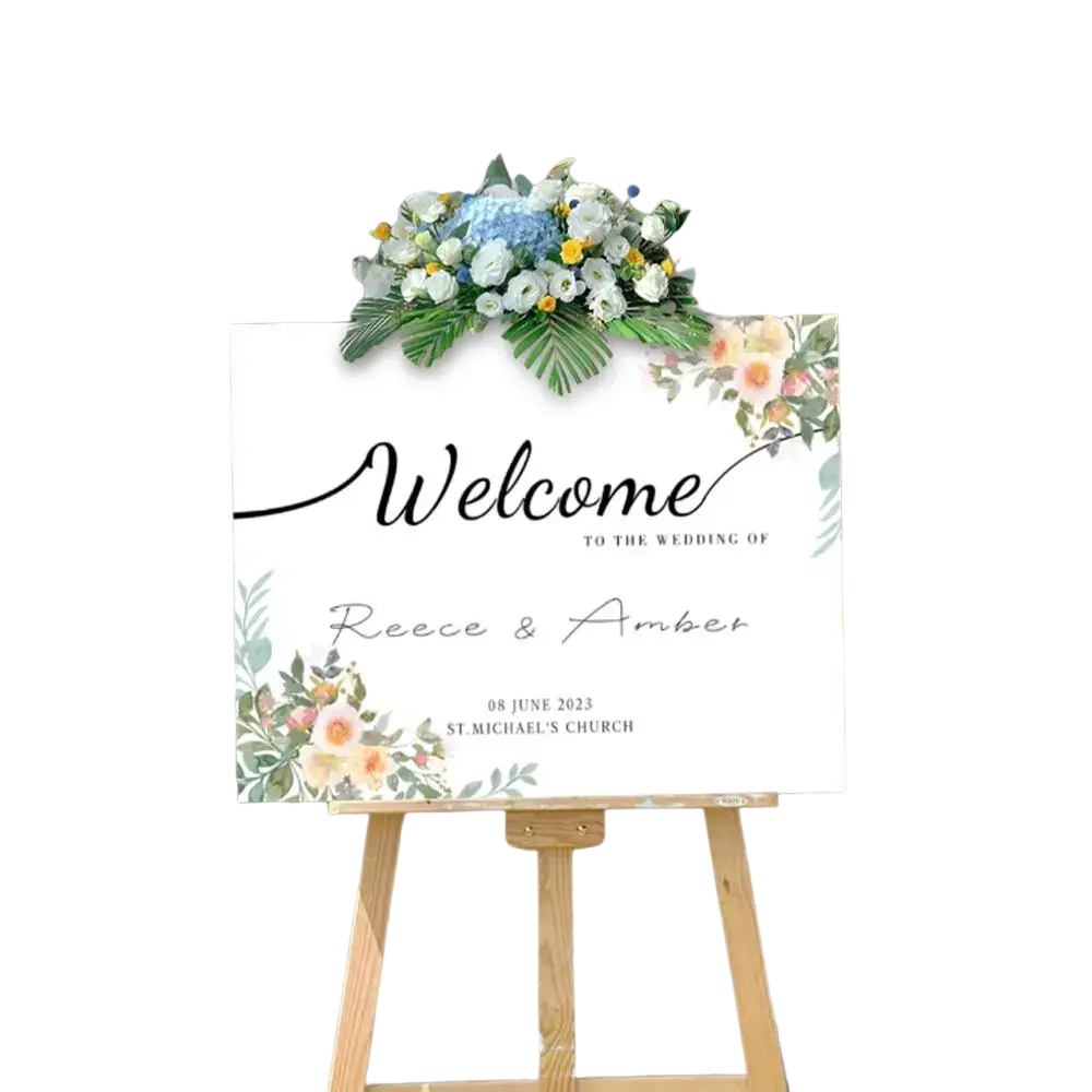 A white floral wedding welcome sign with black cursive lettering and pastel flower illustrations on wooden easel