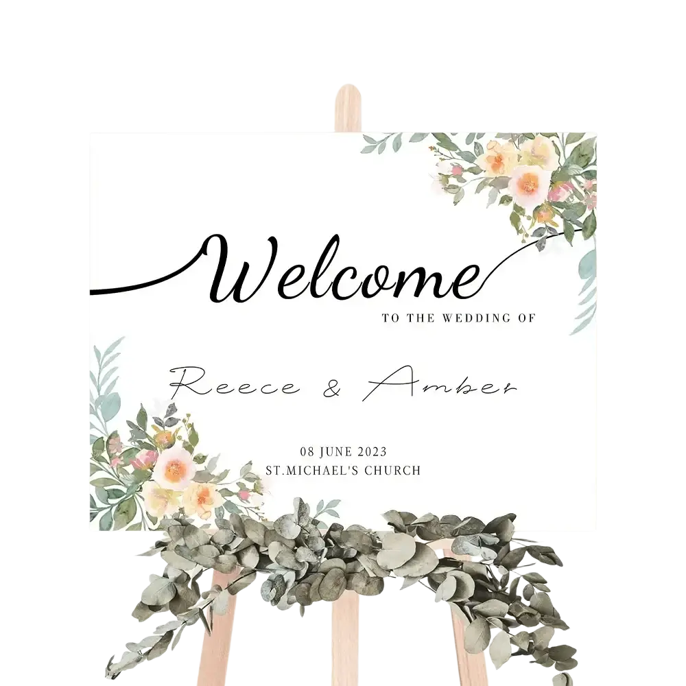 A white custom wedding welcome sign with black cursive lettering and peach pink floral watercolor accents for decor