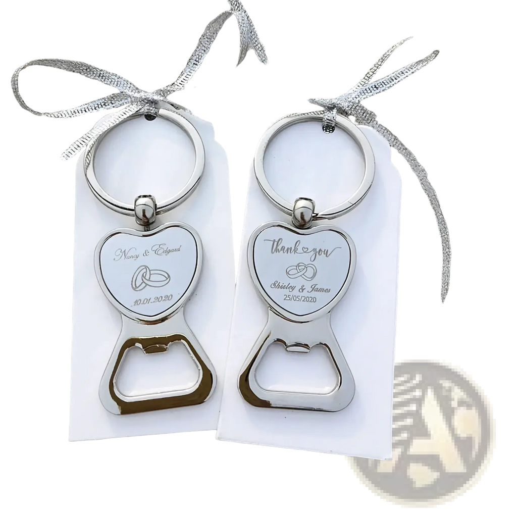 Silver heart-shaped metal bottle opener wedding favors with engraved details and rings attached to white tags with silver ribbon