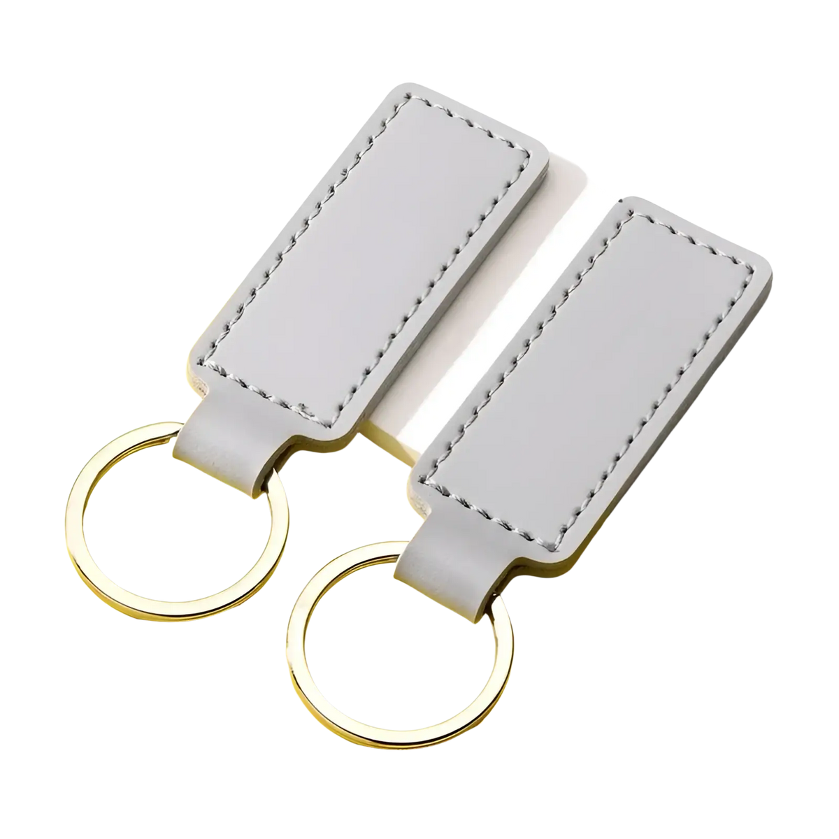 Gray rectangular customized leather keychains with silver-toned metal rings and stitched edges for personal use