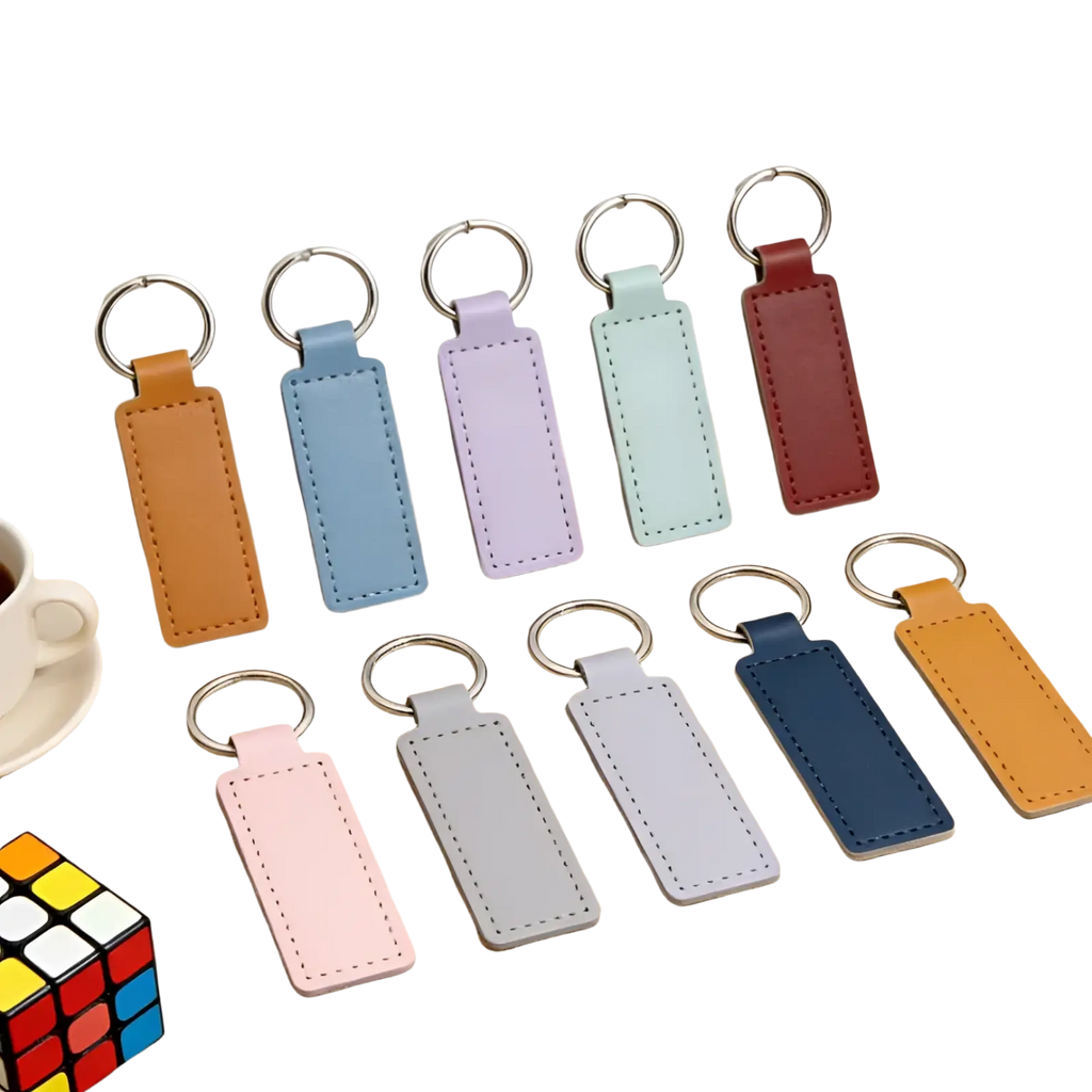 Set of ten pastel-colored rectangular leather keychains with stitched edges and silver metal rings for customization