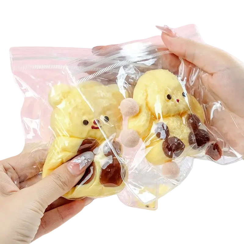 Yellow plush chick squishy toy with brown patches and pink pom-poms in clear packaging for stress relief sensory use
