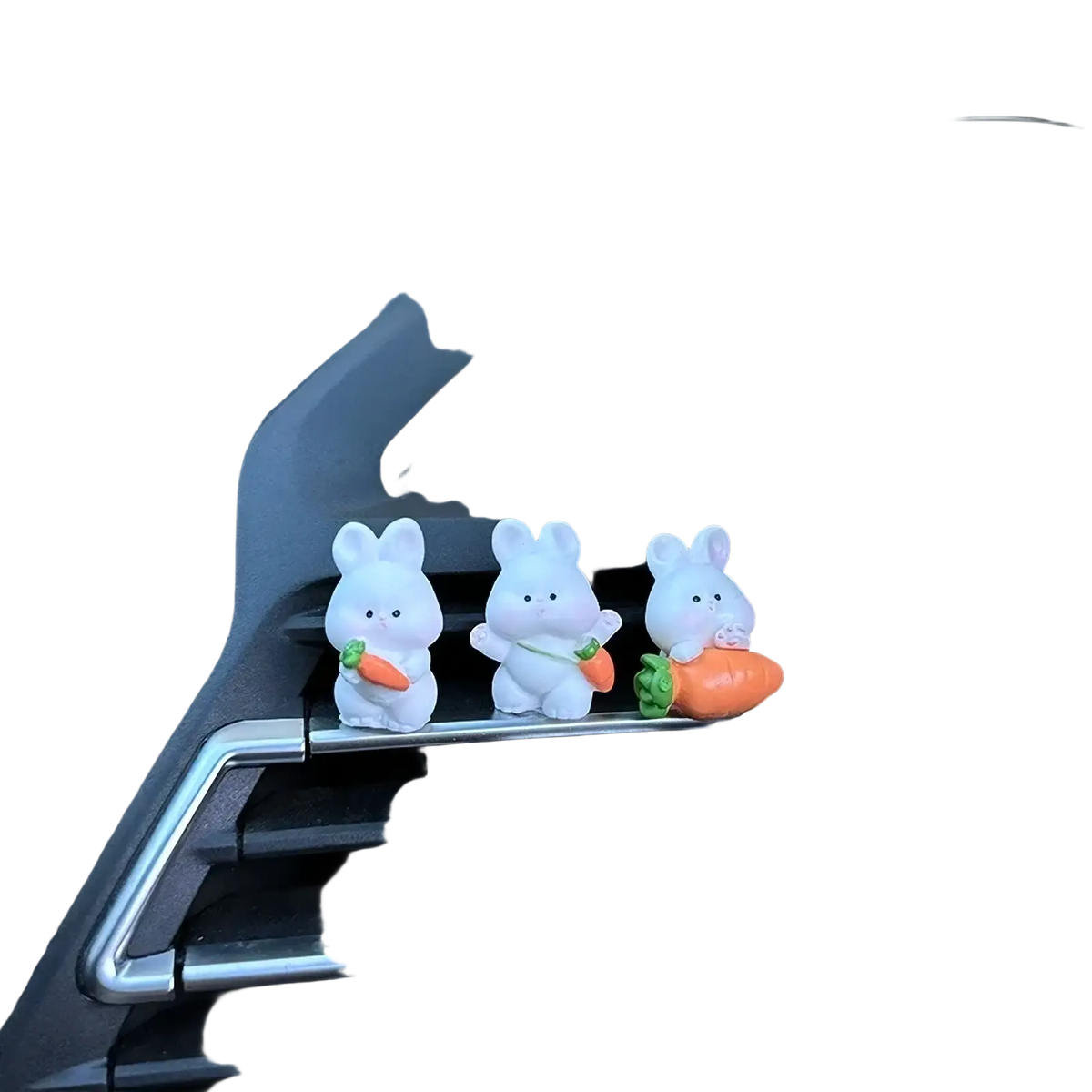 Three white plastic bunny figurines holding orange and green carrot ornaments for cute car dashboard decor