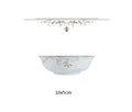A delicate white ceramic bowl with gold leaf floral vine patterns and a metallic rim complementing a classic stainless steel flatware set