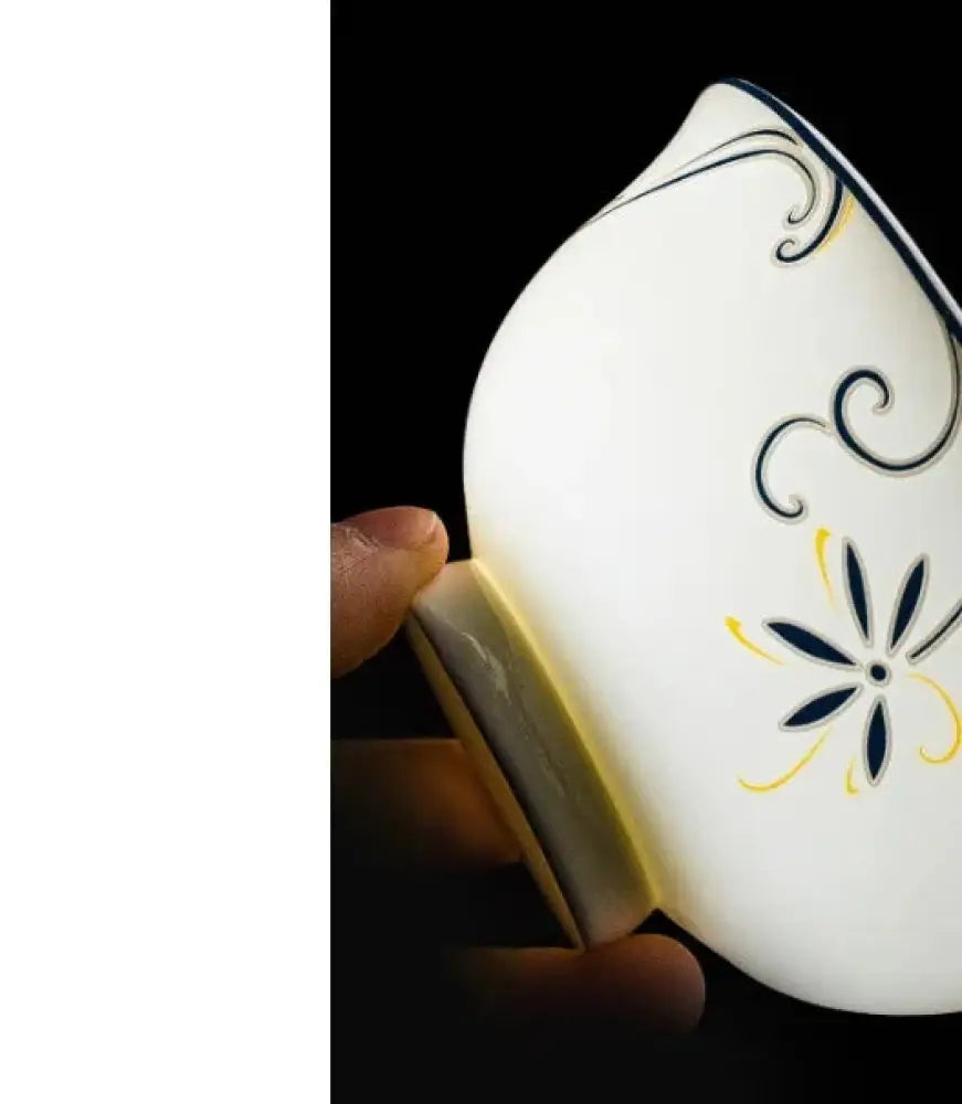 White ceramic bowl with delicate black and yellow floral patterns accompanying classic stainless steel flatware set