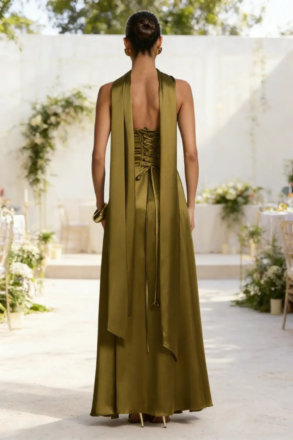 Vista trasera de un elegante vestido de noche sin tirantes de satén verde oliva, con escote drapeado y detalle de cordones en la espalda.