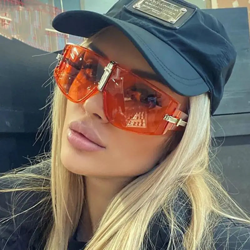 Orange translucent shield-shaped vintage UV400 oversized sunglasses with gold-tone metal accents and a sleek modern design.