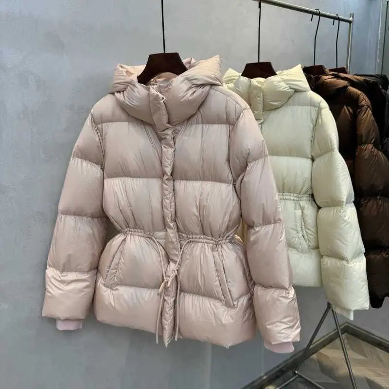 Beige hooded puffer jacket for women with quilted cotton material and a drawstring waist.