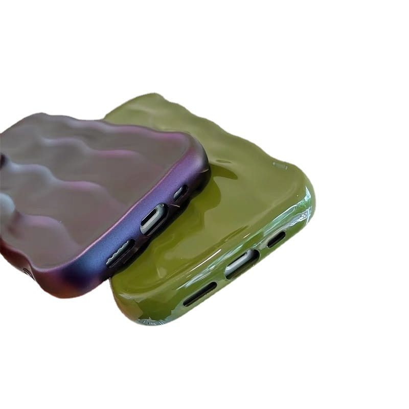 Two glossy, wave-patterned Wavy Liquid Silicone iPhone cases in gradient purple and blue hues and solid olive green with precise cutouts for ports shown from the back side.