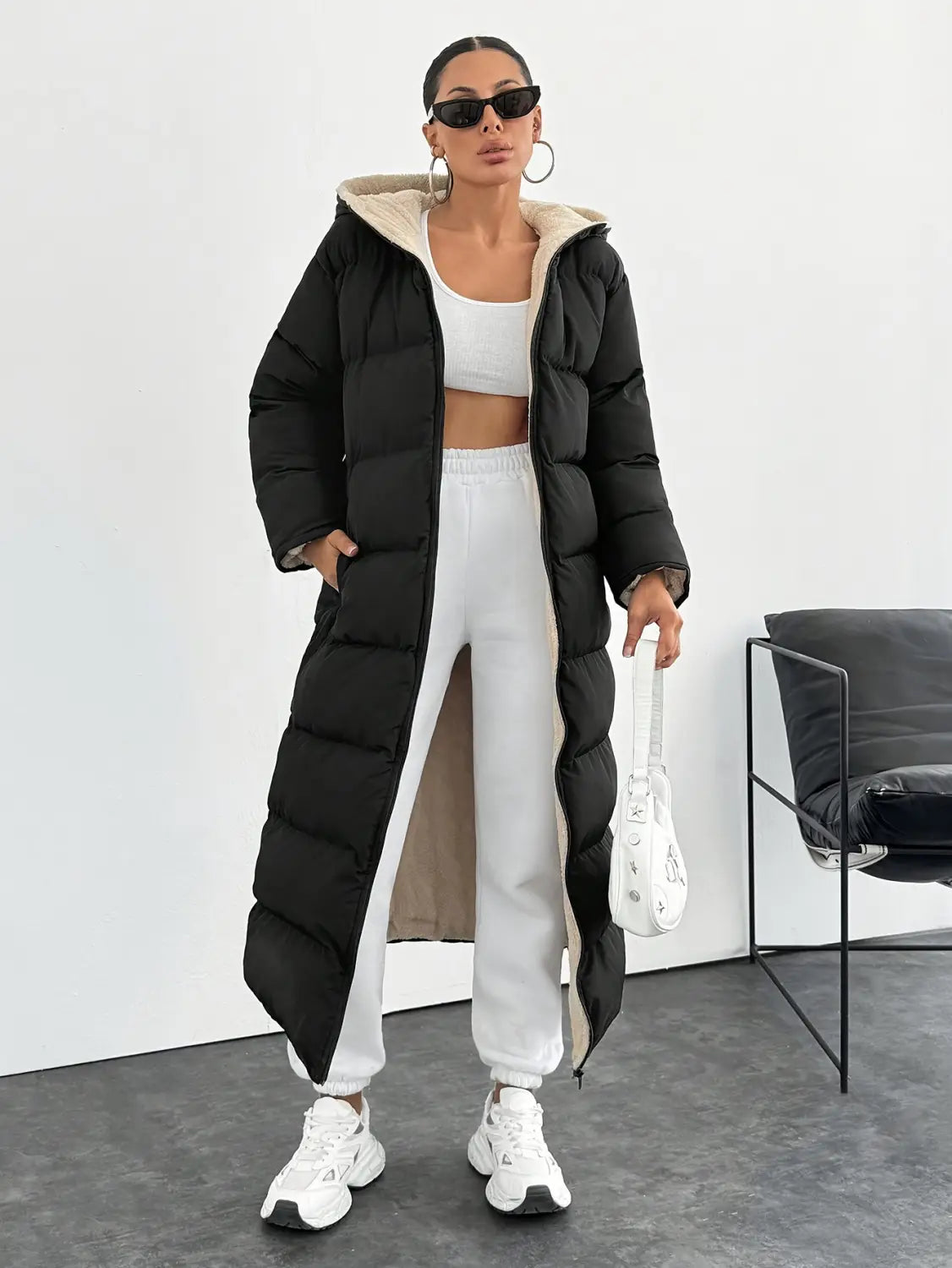 Black hooded quilted long puffer coat in black with a beige-lined hood and detailed quilted design.