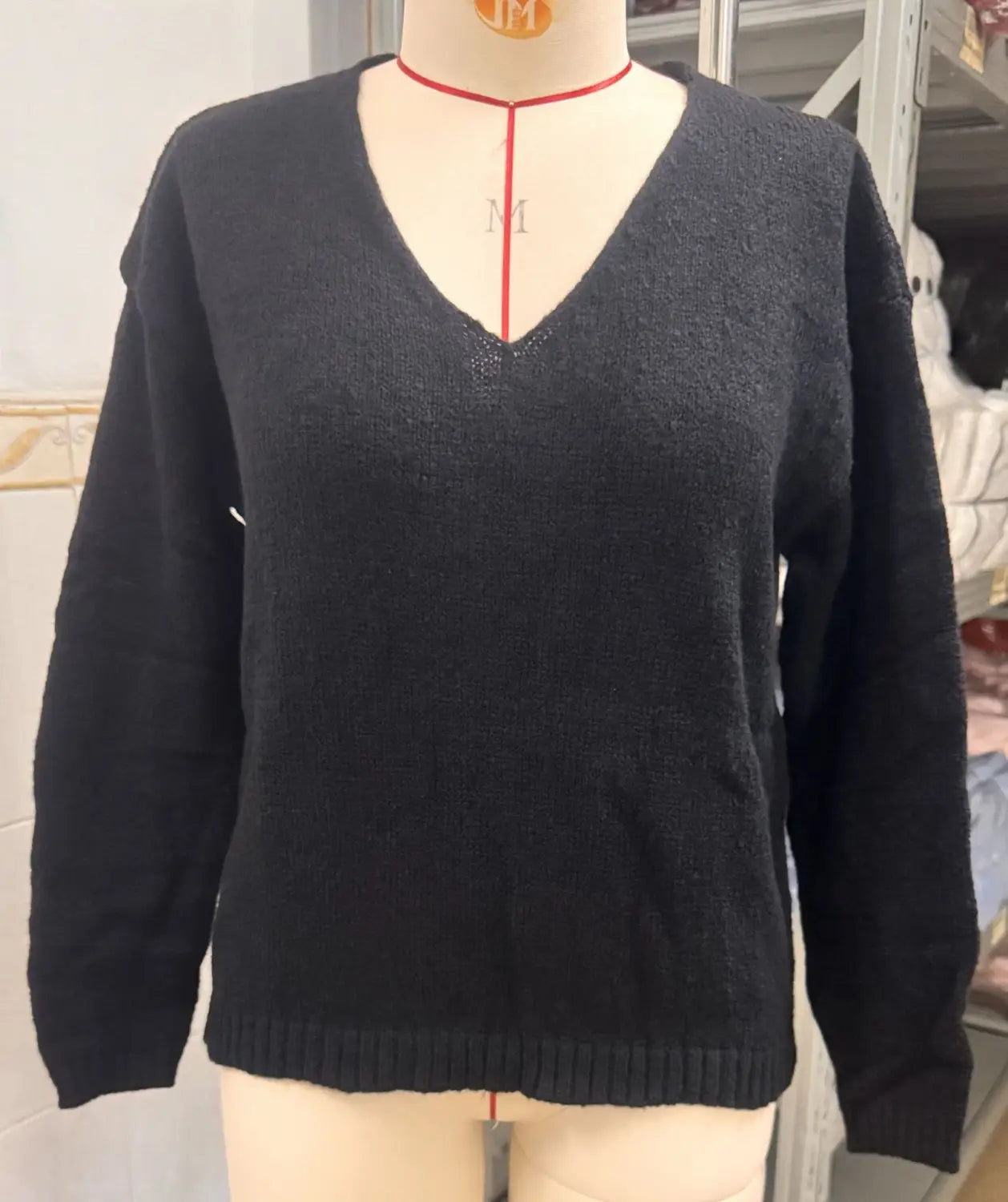 Schwarzer V-Ausschnitt-Strickpullover mit überschnittener Schulterpartie und breitem Saum, mit gerippten Bündchen und Saum in weichem Strickmaterial.