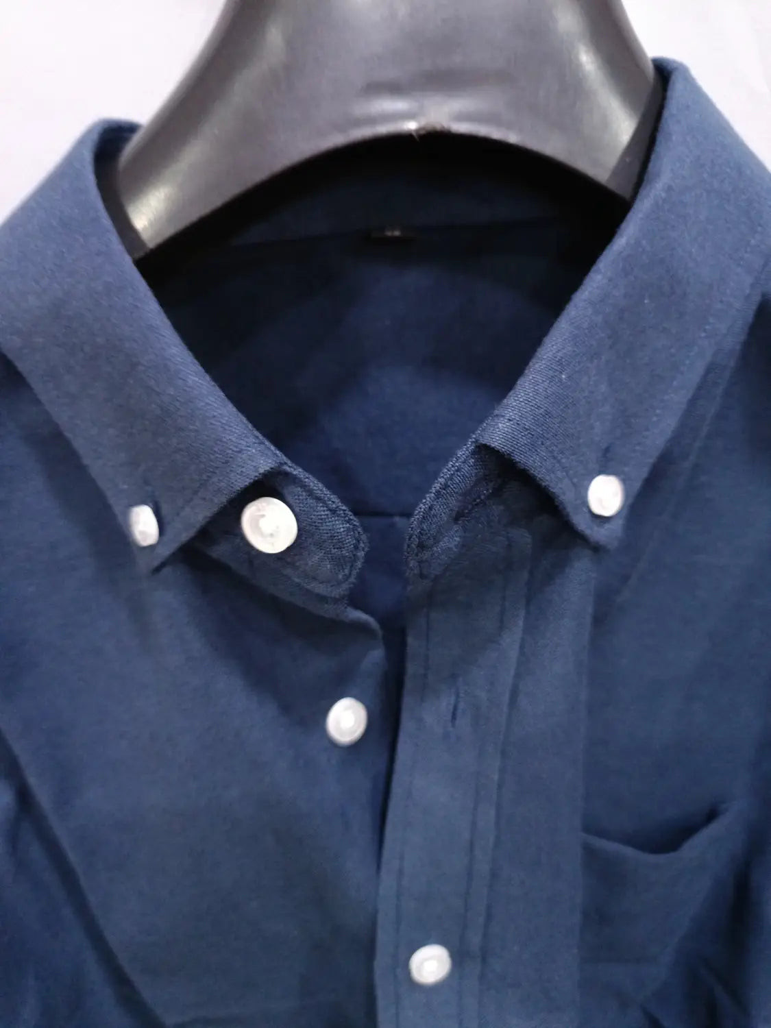 Ein dunkelblaues Herren-Oxford-Freizeithemd mit weißen Knöpfen und einem Baumwoll-Mischgewebe mit Textur.