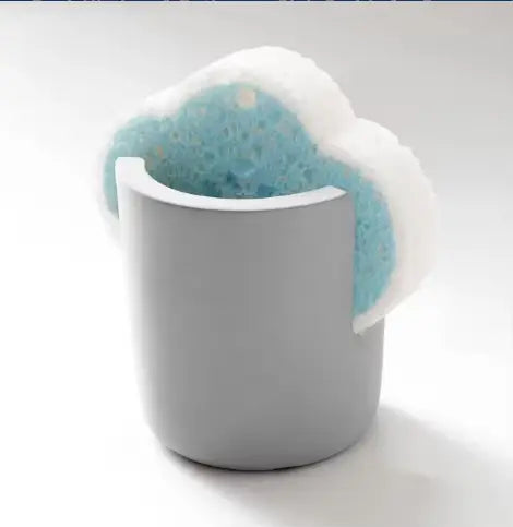 a gray cylindrical diatom mud sponge rack kitchen sink caddy holder cradles a blue and white soft porous scrubbing sponge
