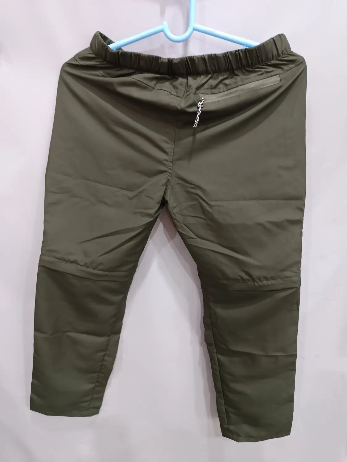 Convertible tactical hiking pants in olive green lightweight nylon with an elastic waistband and front zipper detail.